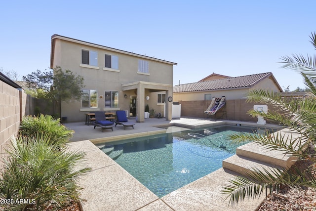 back of house with stucco siding, a fenced backyard, a fenced in pool, and a patio