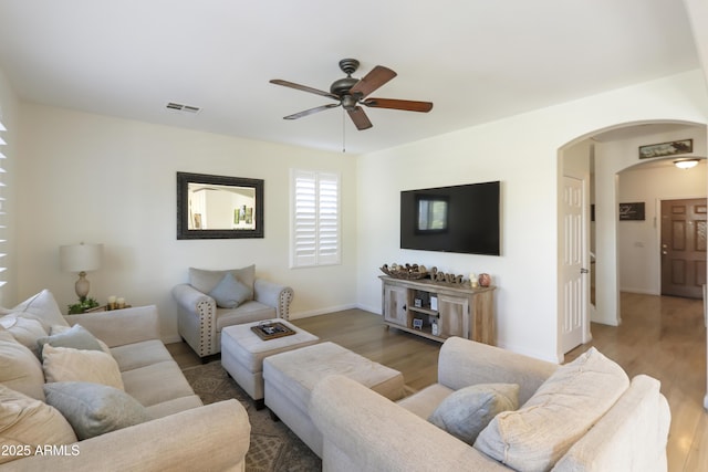 living area with dark wood-style floors, arched walkways, visible vents, and baseboards