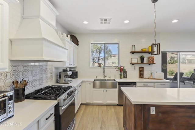 kitchen featuring stainless steel appliances, white cabinets, light countertops, and premium range hood