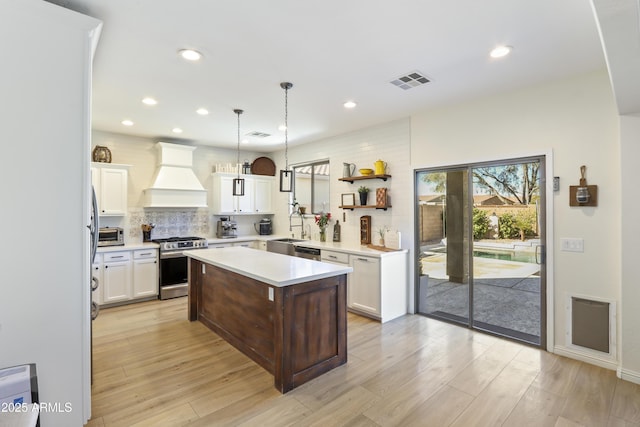 kitchen with premium range hood, visible vents, light countertops, appliances with stainless steel finishes, and pendant lighting