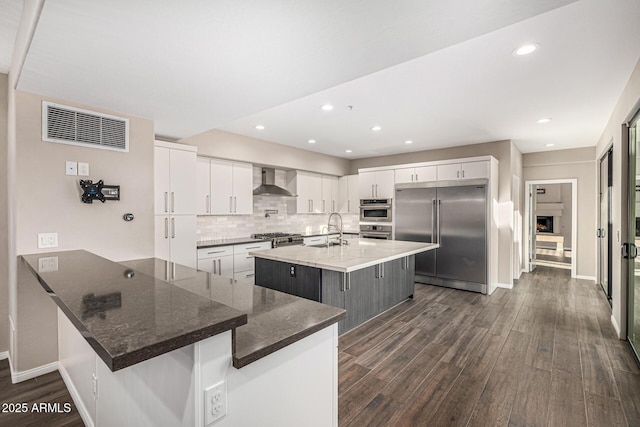 7439 E Beryl Ave, Scottsdale, AZ 85258 - kitchen featuring appliances with stainless steel finishes, a sink, wall chimney range hood, dark wood-style flooring, and a peninsula