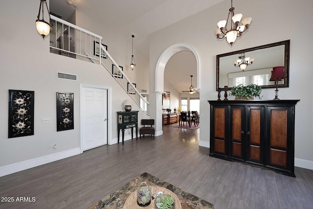 entrance foyer with ceiling fan with notable chandelier, high vaulted ceiling, and dark hardwood / wood-style flooring