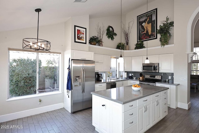 kitchen featuring a center island, white cabinets, pendant lighting, backsplash, and stainless steel appliances