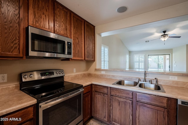 kitchen featuring appliances with stainless steel finishes, lofted ceiling, sink, kitchen peninsula, and ceiling fan