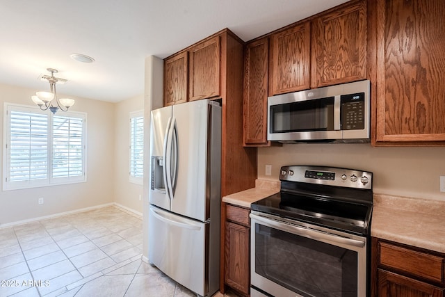 kitchen with light tile patterned floors, appliances with stainless steel finishes, and a chandelier