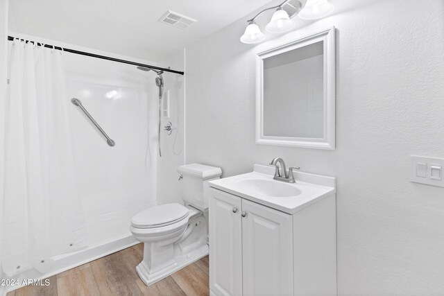 bathroom featuring vanity, toilet, hardwood / wood-style flooring, and walk in shower