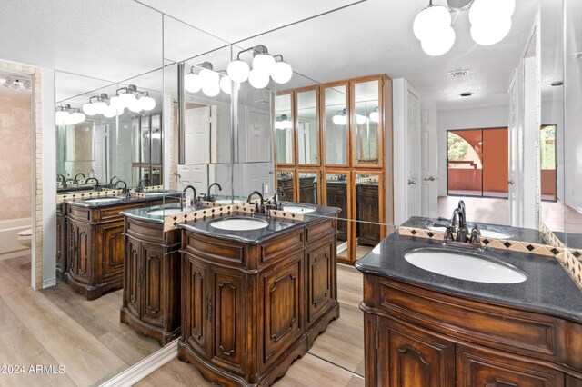 bathroom featuring toilet, a notable chandelier, wood-type flooring, vanity, and a textured ceiling