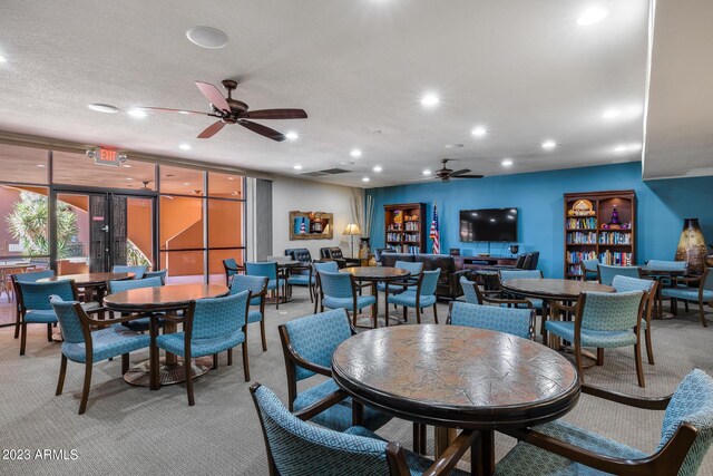 dining space featuring ceiling fan, expansive windows, a textured ceiling, and carpet floors