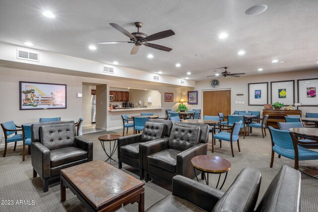 carpeted living room featuring a textured ceiling and ceiling fan