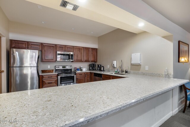 kitchen featuring stainless steel appliances, light stone counters, sink, and kitchen peninsula