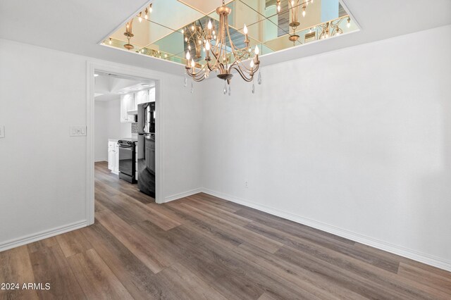 unfurnished room with wood-type flooring and an inviting chandelier