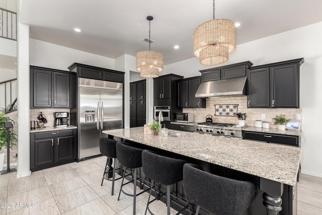 5212 S Seton Ct, Gilbert, AZ 85298 - kitchen featuring appliances with stainless steel finishes, under cabinet range hood, backsplash, a chandelier, and light stone counters