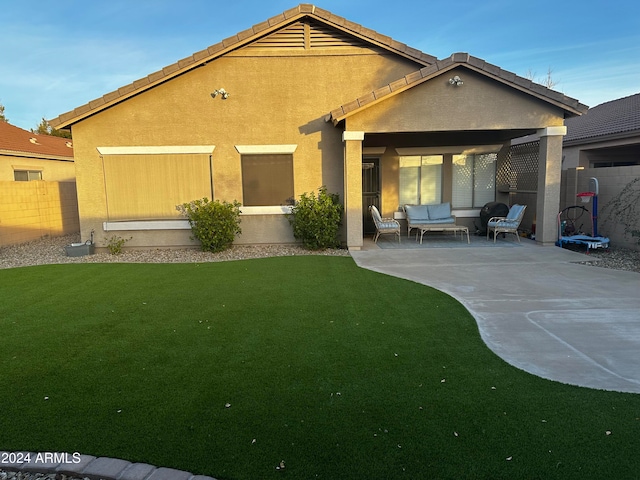 back of property with a lawn, an outdoor hangout area, and a patio area