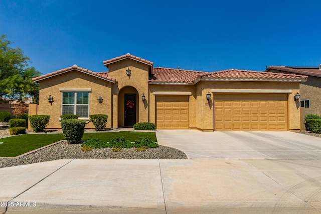 mediterranean / spanish house featuring an attached garage, a tiled roof, concrete driveway, and stucco siding