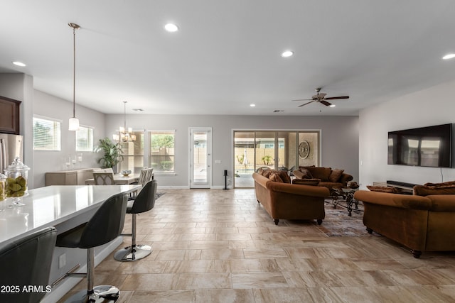 living room featuring ceiling fan with notable chandelier, baseboards, and recessed lighting