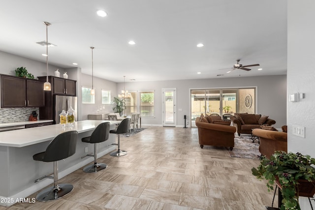 kitchen featuring dark brown cabinetry, visible vents, light countertops, freestanding refrigerator, and decorative backsplash