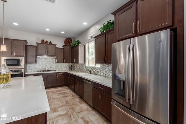 kitchen featuring light countertops, appliances with stainless steel finishes, dark brown cabinetry, and under cabinet range hood