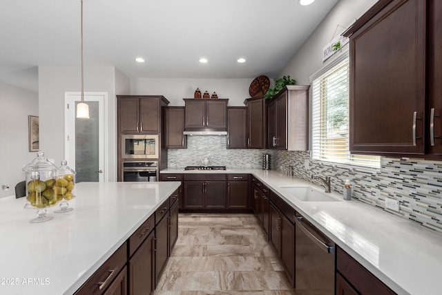 kitchen featuring appliances with stainless steel finishes, light countertops, a sink, and dark brown cabinets