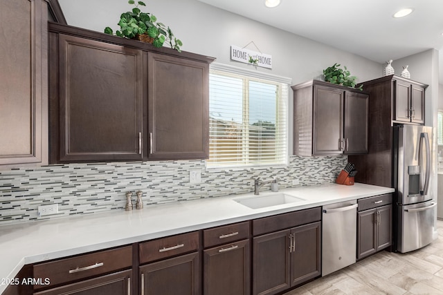 kitchen featuring dark brown cabinetry, tasteful backsplash, stainless steel appliances, light countertops, and a sink