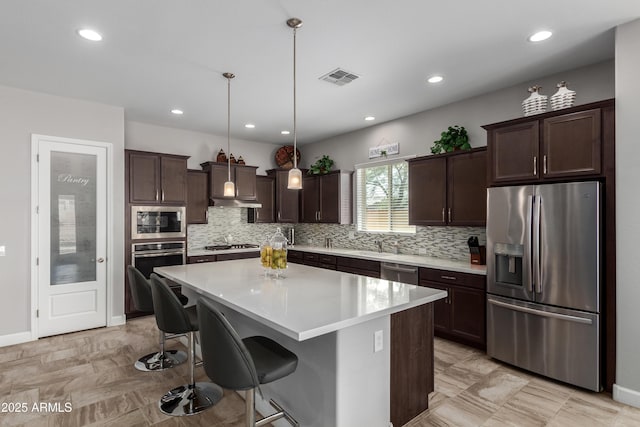 kitchen featuring stainless steel appliances, dark brown cabinets, visible vents, and a center island