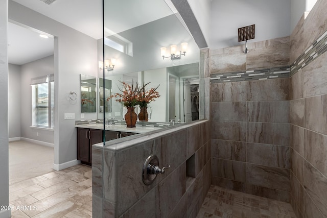 full bathroom featuring baseboards, tiled shower, and vanity