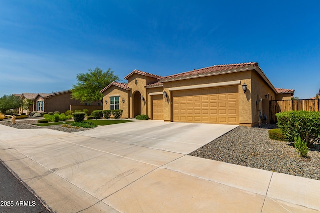 mediterranean / spanish home with driveway, a tile roof, an attached garage, fence, and stucco siding