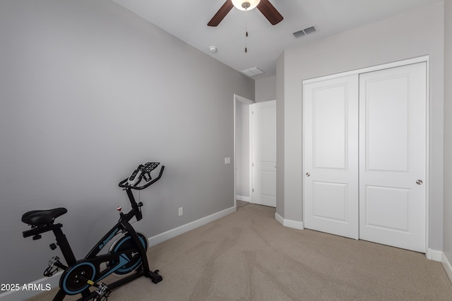 exercise area featuring baseboards, visible vents, ceiling fan, and light colored carpet