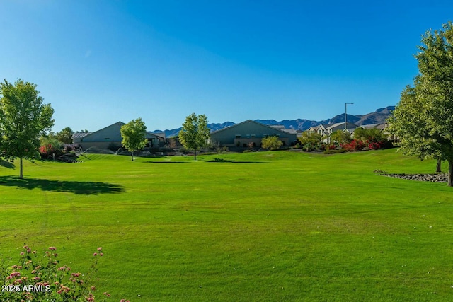 surrounding community with a mountain view and a yard