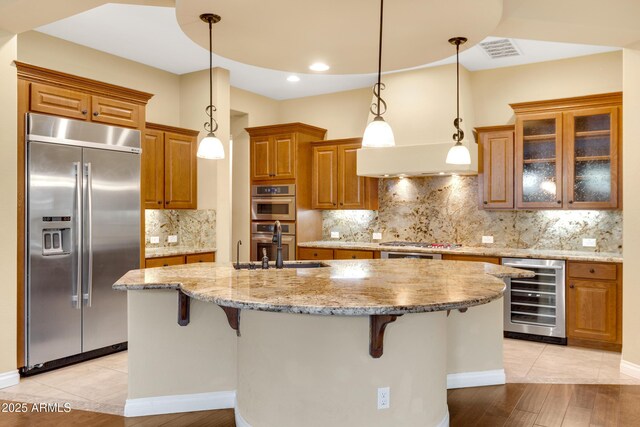 1620 E Sattoo Way, Queen Creek, AZ 85140 - kitchen with stainless steel appliances, beverage cooler, a sink, brown cabinetry, and a breakfast bar