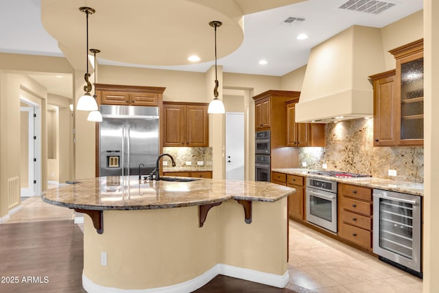 1620 E Sattoo Way, Queen Creek, AZ 85140 - kitchen with beverage cooler, appliances with stainless steel finishes, a sink, premium range hood, and brown cabinets
