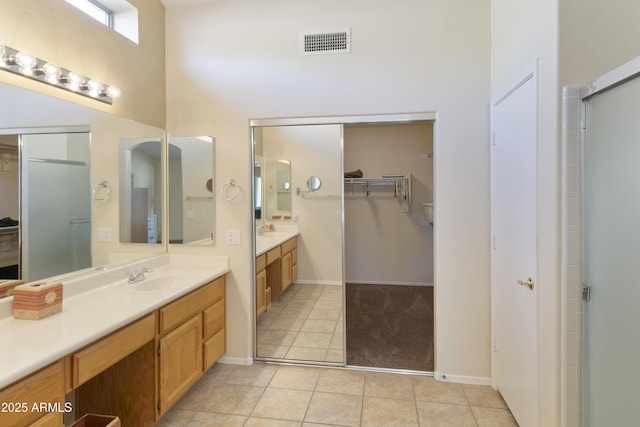 bathroom with vanity, a shower with door, tile patterned floors, and a high ceiling