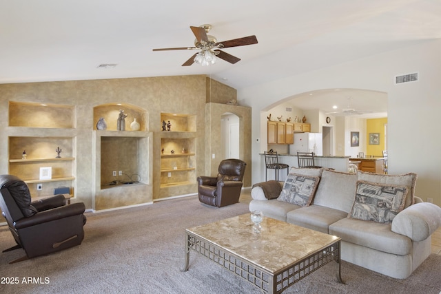 carpeted living room with vaulted ceiling, built in features, and ceiling fan