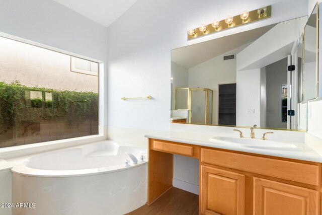 bathroom with vanity, lofted ceiling, hardwood / wood-style flooring, and independent shower and bath