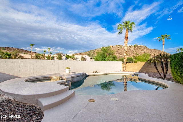 view of swimming pool with a patio, a mountain view, and an in ground hot tub