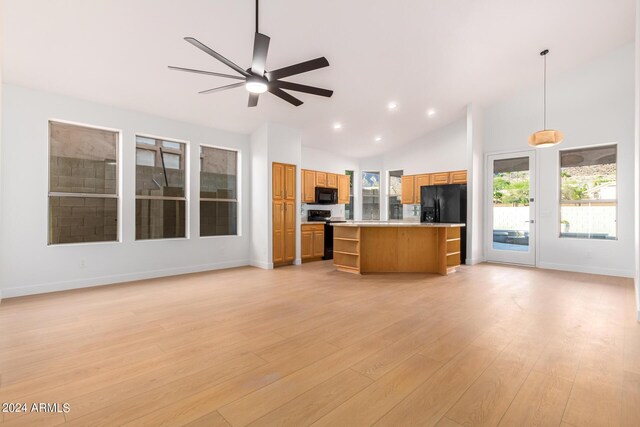 kitchen featuring light wood-type flooring, black appliances, light stone countertops, and a center island