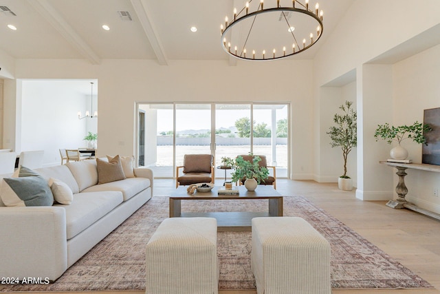 living room with light wood-type flooring, a chandelier, beam ceiling, a towering ceiling, and a water view