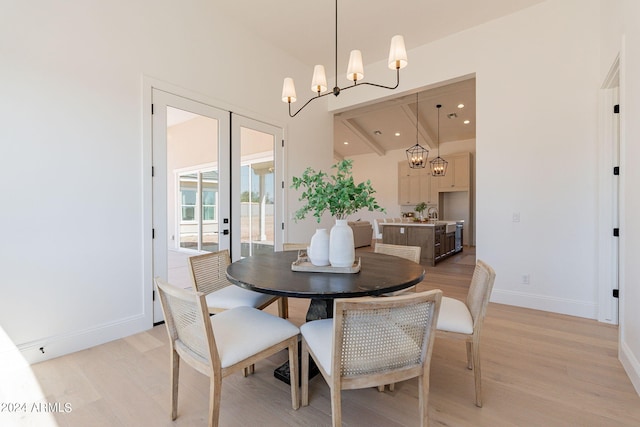 dining room with a notable chandelier, light hardwood / wood-style floors, and french doors