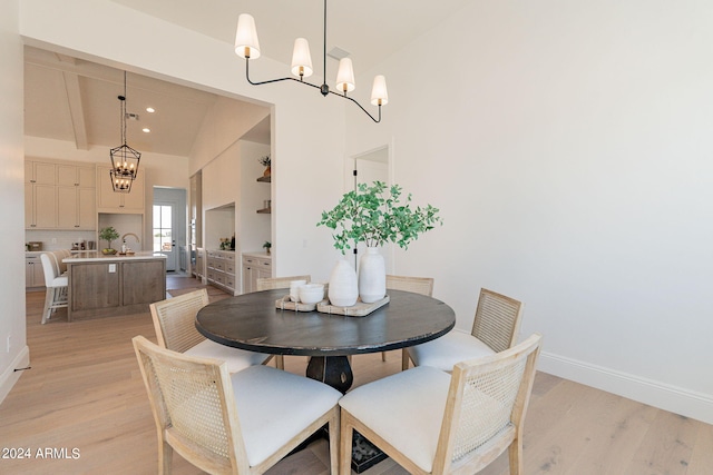 dining space featuring vaulted ceiling with beams, light hardwood / wood-style floors, sink, and a notable chandelier