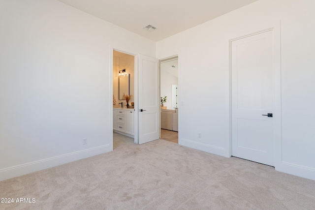 unfurnished bedroom with light colored carpet and ensuite bath