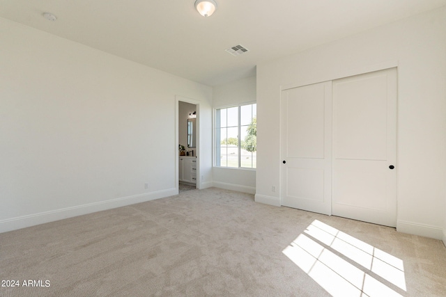 unfurnished bedroom featuring light carpet and a closet