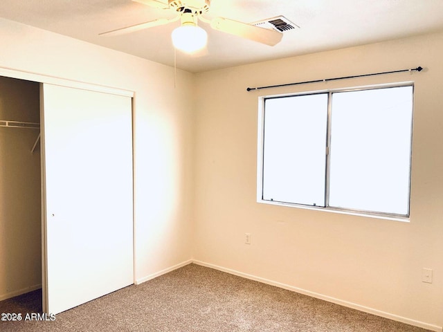 unfurnished bedroom featuring carpet flooring, a ceiling fan, visible vents, baseboards, and a closet