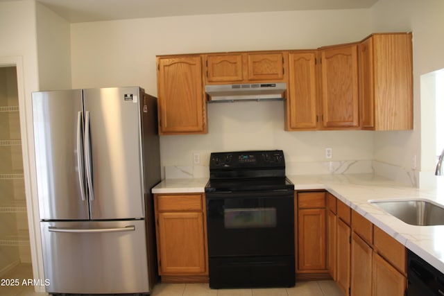 kitchen featuring light countertops, light tile patterned flooring, a sink, under cabinet range hood, and black appliances