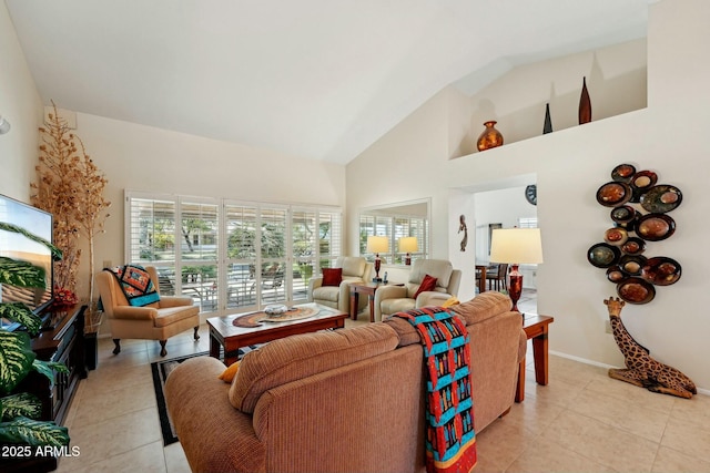 living room featuring light tile patterned floors, baseboards, plenty of natural light, and high vaulted ceiling