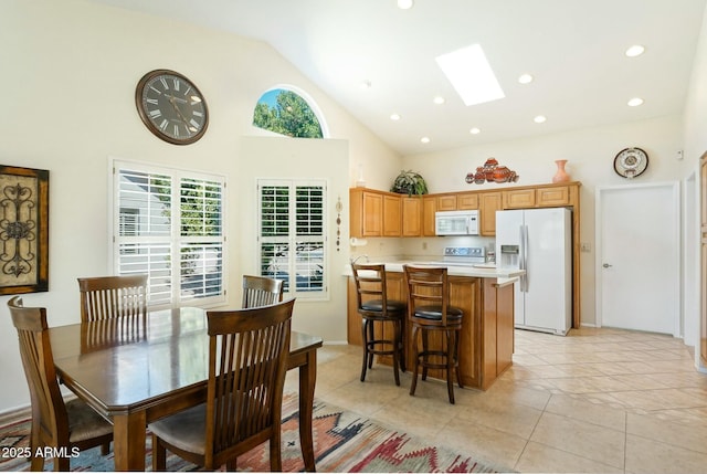 dining room with light tile patterned floors, high vaulted ceiling, recessed lighting, and a skylight