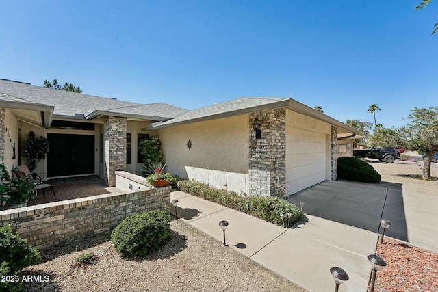 view of front of house featuring stucco siding, driveway, stone siding, an attached garage, and a shingled roof