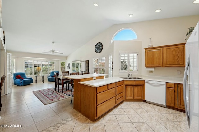 kitchen with a sink, white appliances, a peninsula, and light tile patterned floors