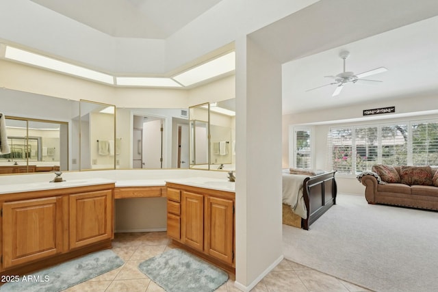 ensuite bathroom with vanity, a skylight, ceiling fan, ensuite bathroom, and tile patterned floors