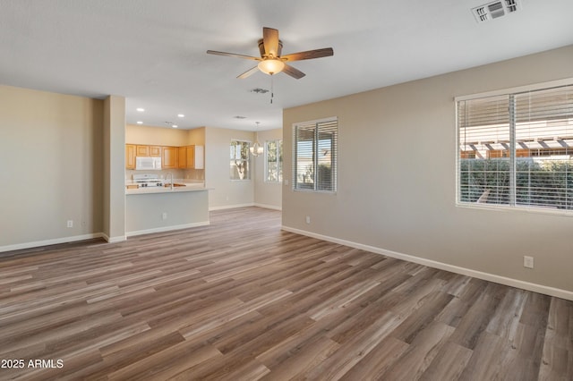 unfurnished living room with dark hardwood / wood-style floors, sink, and ceiling fan with notable chandelier