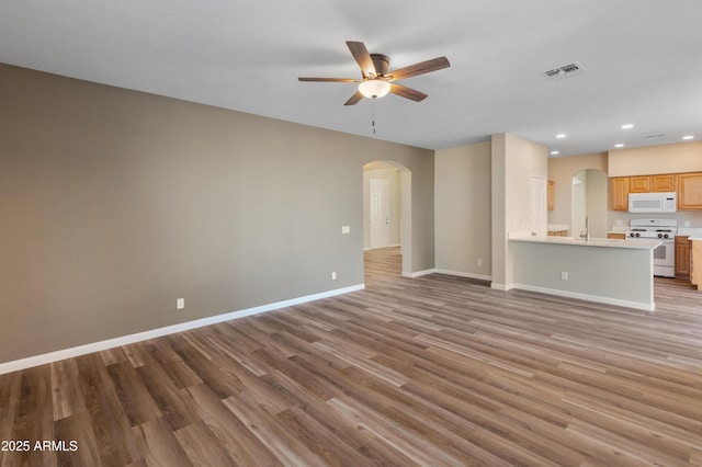 unfurnished living room featuring light hardwood / wood-style floors, sink, and ceiling fan