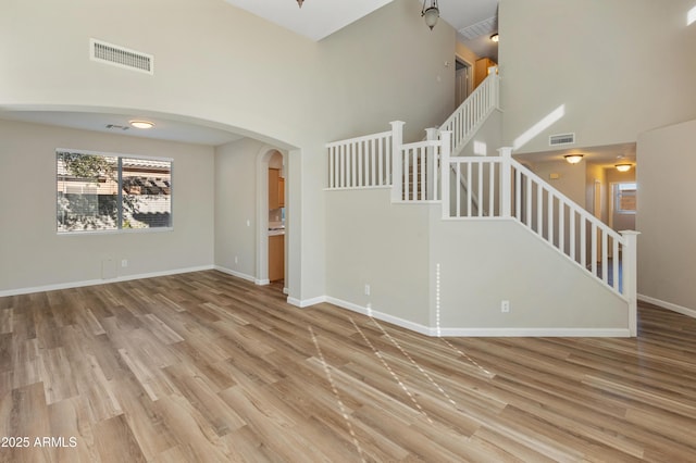 unfurnished living room with hardwood / wood-style flooring and a towering ceiling